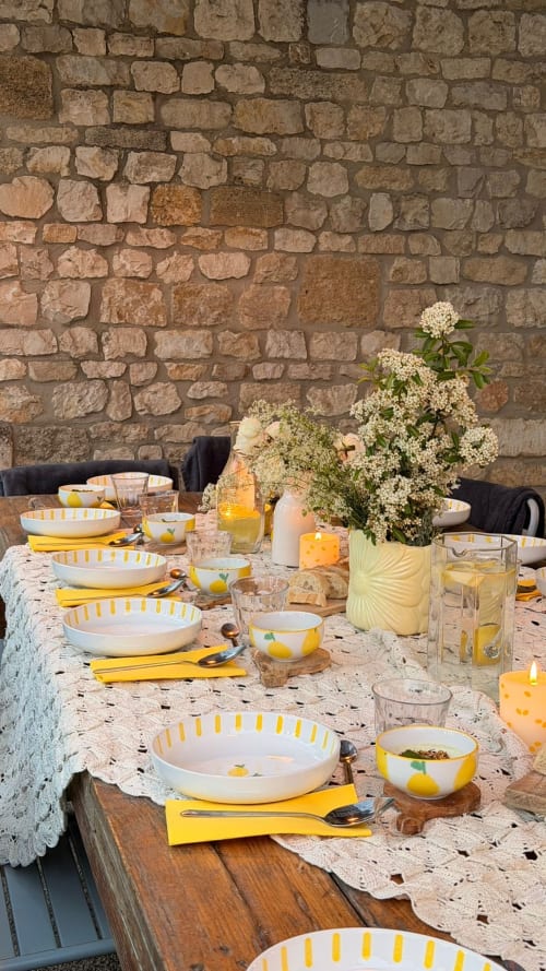 Outdoor dining table with yellow-accented dishware and white flowers at Mas des Ecoliers, Provence