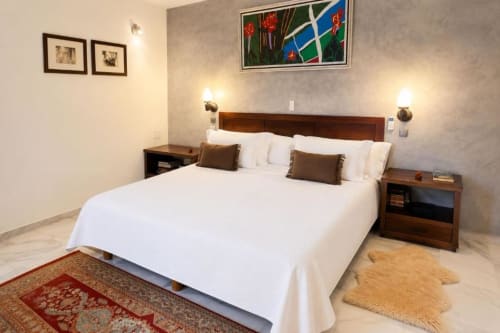 Dormitorio doble moderno en Hacienda Blanca Marbella con ropa de cama blanca, muebles de madera y arte contemporáneo