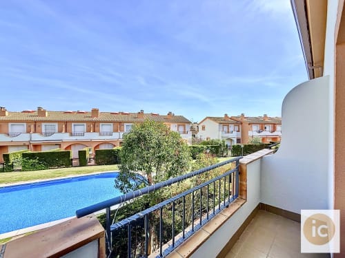 Balcón de cottage en Estartit con vistas a piscina azul, resort mediterráneo y tejados de barro