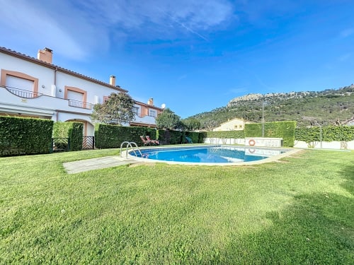 Casa de alquiler en Estartit con piscina azul, césped verde y vistas a las montañas en España