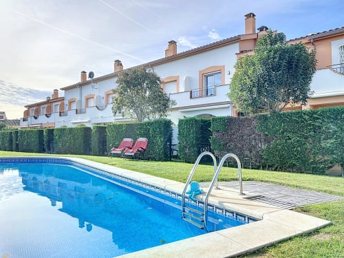 Piscina de resort con tumbonas y casas mediterráneas en la casa de alquiler Estartit, L'Estartit España
