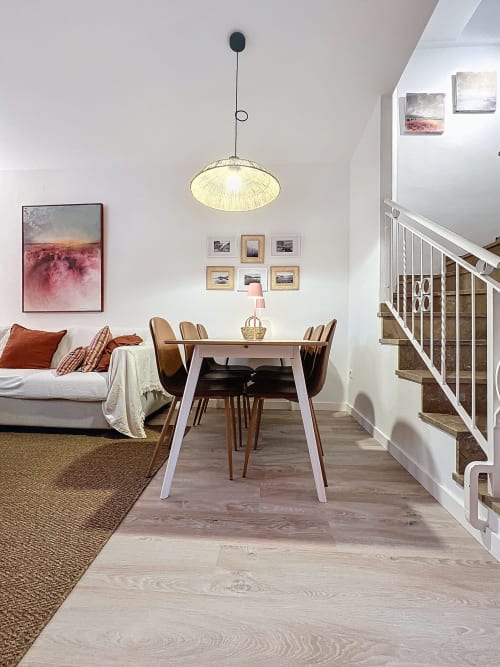 Sala de estar moderna y abierta en La Bella Lola con comedor, asientos, lámpara colgante y escaleras