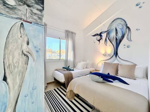 Dormitorio luminoso en la casa rural Estartit con dos camas, arte de pared con ballena náutica, alfombra rayada y vistas al mar