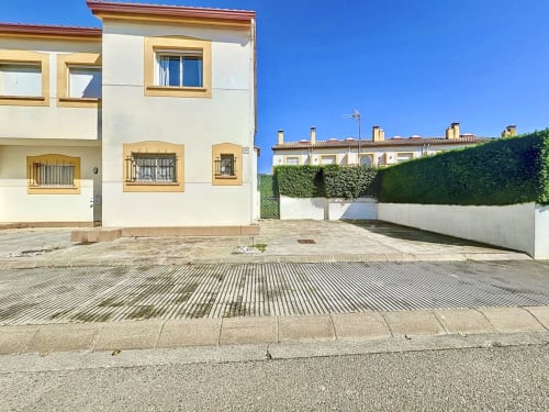 Casa de alquiler La Vela en L'Estartit con fachada blanca y amarilla, camino pavimentado y patio cerrado por setos