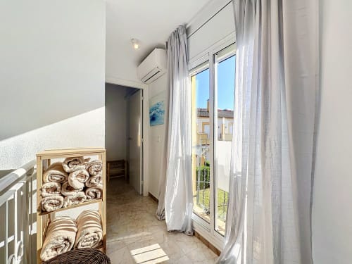 Baño luminoso con estanterías de almacenaje, accesorios modernos y puertas de cristal con vistas a la piscina
