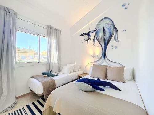 Luminoso dormitorio doble en Estartit Rental con mural temático de ballenas, camas blancas y vistas al mar desde la ventana