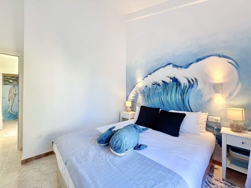 Dormitorio moderno de la casa rural La Vela en L'Estartit con mural de olas, ropa de cama blanca y decoración náutica