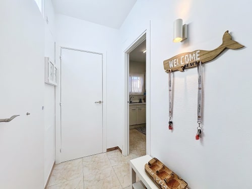 Entrada luminosa de la casa La Vela en Estartit con decoración temática de ballena y ganchos náuticos