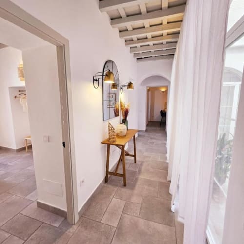 Pasillo moderno con mesa de madera, lámpara colgante de latón y arco blanco en el apartamento Casa De La Cruz Vejer, Vejer de la