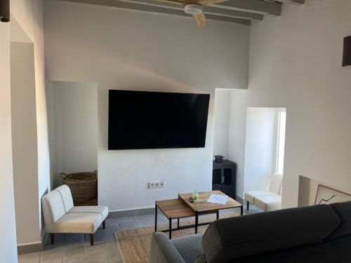 Sala moderna en apartamento Casa De La Cruz Vejer con TV montado, sofá, mesa de café de madera y decoración neutral