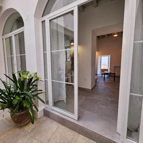 Entrada del apartamento Casa De La Cruz Vejer con puertas de cristal, plantas en maceta y vistas del interior en Vejer de la Frontera