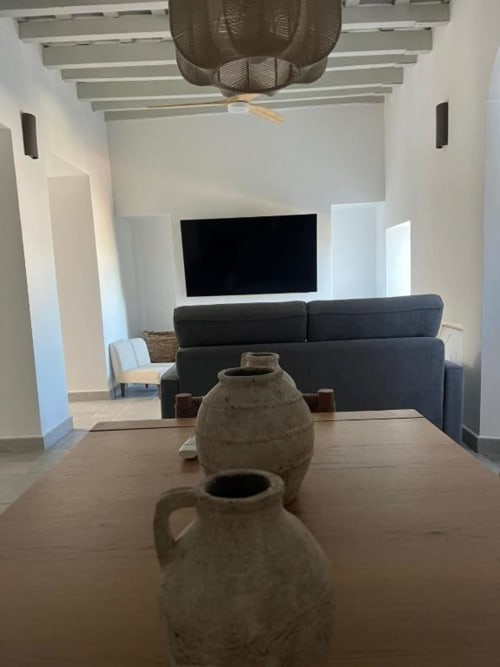 Sala de estar moderna en apartamento Casa De La Cruz Vejer con cerámica artesanal, mesa de comedor, sofá oscuro y TV en pared