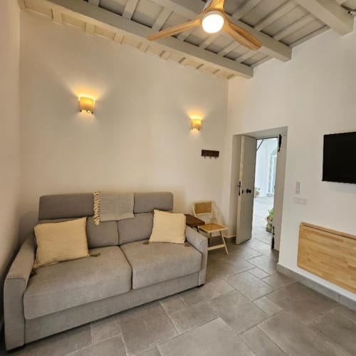 Moderno apartamento estudio en Vejer de la Frontera con sofá cama gris, ventilador de techo, apliques de pared y vistas a la ciudad