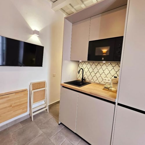 Moderna cocina estudio en Casa De La Cruz Vejer con muebles blancos, encimera de madera, cocina negra y salpicadero geométrico