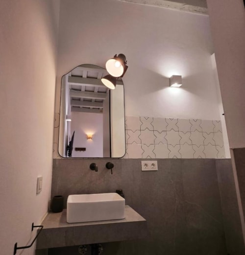 Baño moderno en Casa De La Cruz Vejer con lavabo tipo vasija blanco, espejo redondo, dos apliques de pared y azulejos geométricos