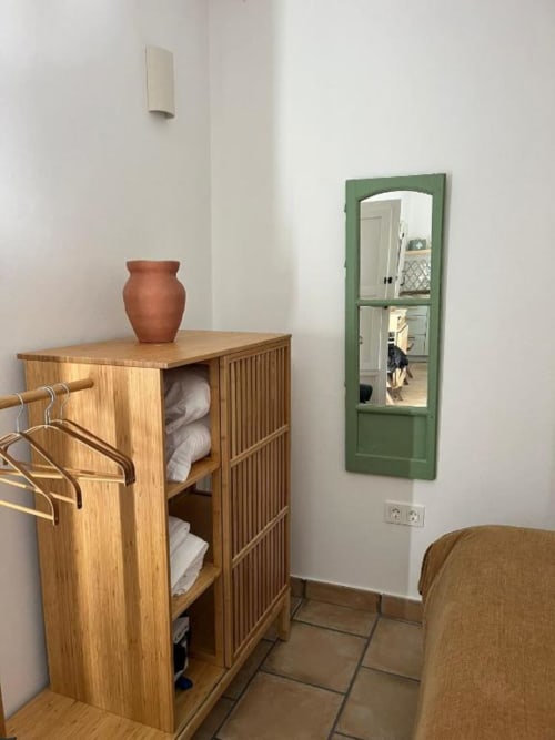 Rincón acogedor del dormitorio en Casa De La Cruz Vejer con mueble de madera, jarrón de terracota y espejo de marco verde