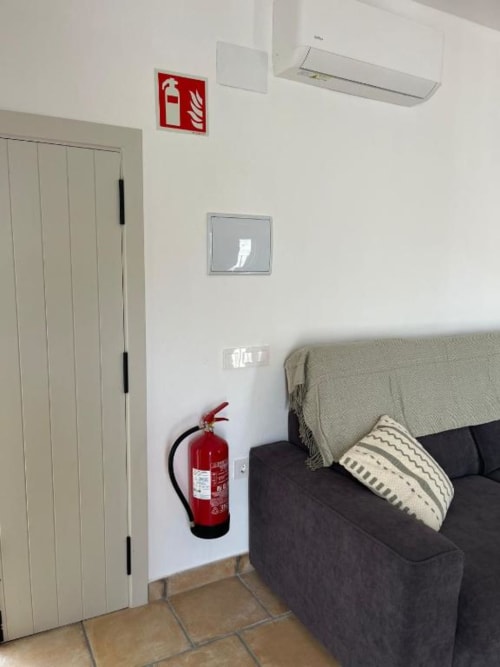 Sala de estar con sofá, extintor rojo, puerta de armario blanca y comodidades modernas en apartamento Casa De La Cruz Vejer