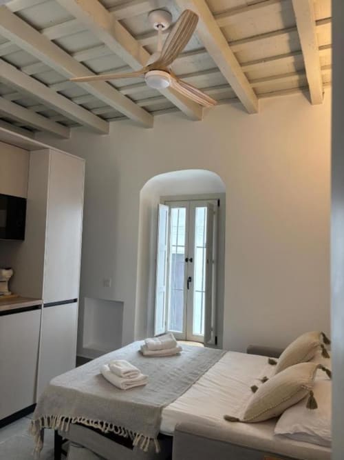 Moderno estudio en Casa De La Cruz Vejer con sofá cama, cocina blanca, puerta arqueada y ventilador de madera