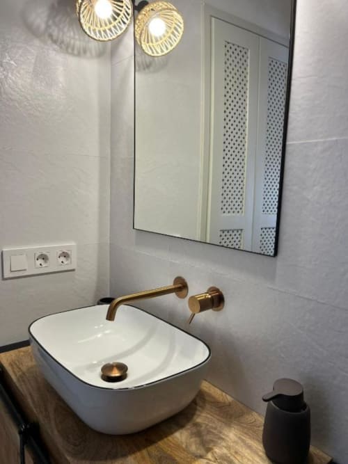 Baño moderno en Casa De La Cruz Vejer con lavabo de cerámica blanca, accesorios de bronce, iluminación colgante y espejo en habitación Deluxe