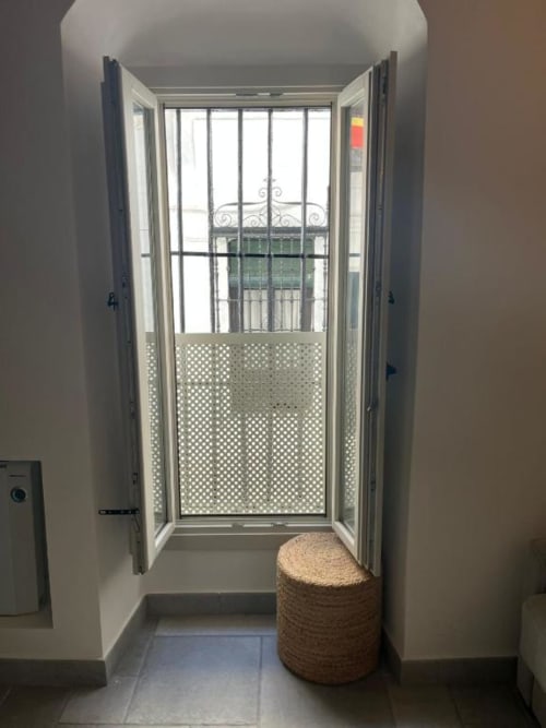 Puertas francesas abiertas hacia un balcón de Vejer con barandillas ornamentales y vistas de la ciudad desde el estudio Casa De La Cruz