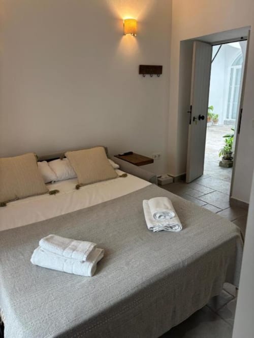 Dormitorio estudio en Casa De La Cruz Vejer con sofá cama, toallas blancas, aplique mural y acceso a patio en Vejer de la Frontera