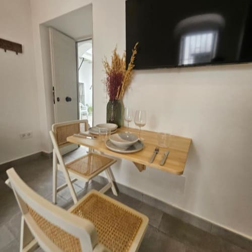 Comedor moderno en Casa De La Cruz Vejer con mesa de madera, sillas de ratán, vajilla y flores secas en Vejer de