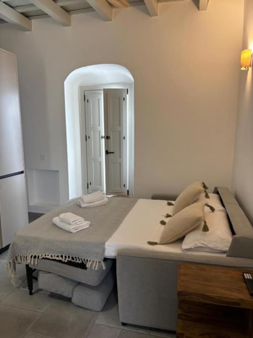Estudio en Casa De La Cruz Vejer con sofá cama, puertas de armario arqueadas blancas y decoración en tonos beige en Vejer de la
