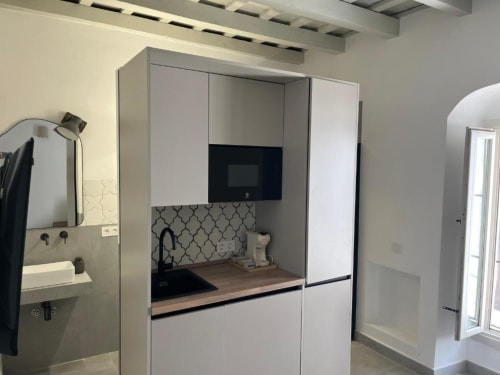 Cocina moderna en Casa De La Cruz Vejer con armarios blancos, encimera de madera, microondas integrado y azulejos geométricos