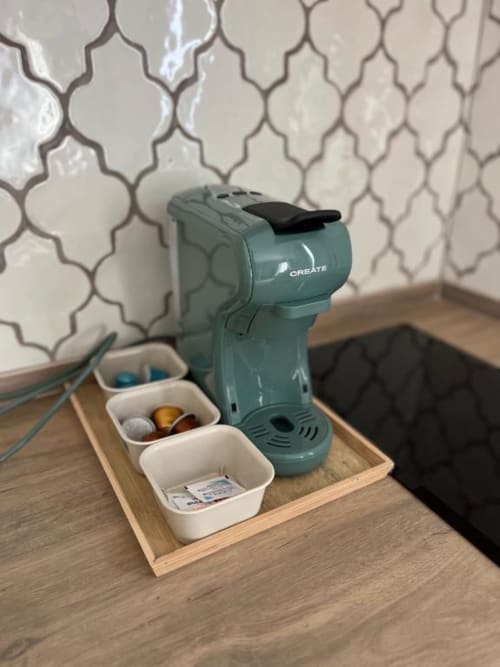 Cafetera CREATE verde con cápsulas y contenedores blancos sobre bandeja de madera en la Deluxe Studio de Casa De La Cruz Vejer