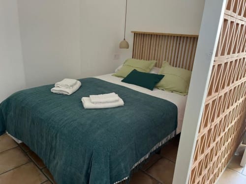 Dormitorio moderno en Casa De La Cruz Vejer con ropa de cama turquesa, cabecero de madera, almohadas verdes y toallas blancas