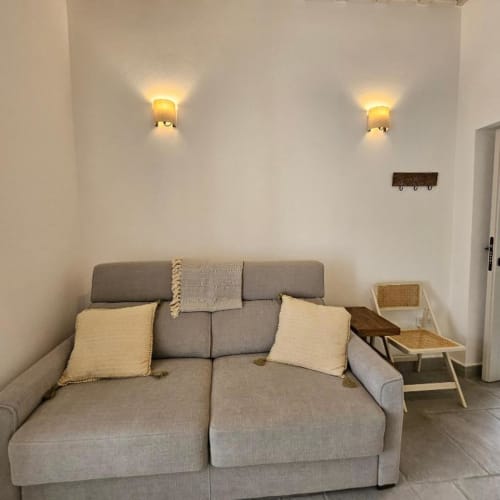 Sofá cama gris con almohadas color crema en estudio de Casa De La Cruz Vejer, Vejer de la Frontera, España