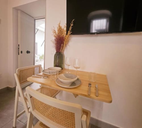 Comedor del estudio Casa De La Cruz Vejer con mesa de madera, sillas de ratán, servicios de mesa y decoración