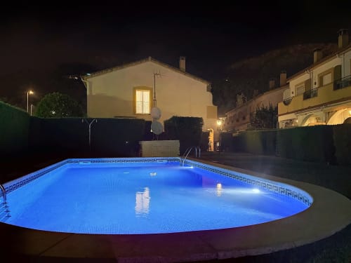 Piscina ovalada iluminada por la noche con luces LED azules en la casa de alquiler Estartit en L'Estartit, España