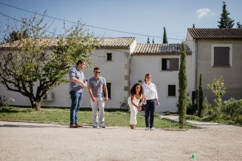 Family walking on grounds of Mas des Ecoliers, a Provençal family home in Chateaurenard with white stone buildings and