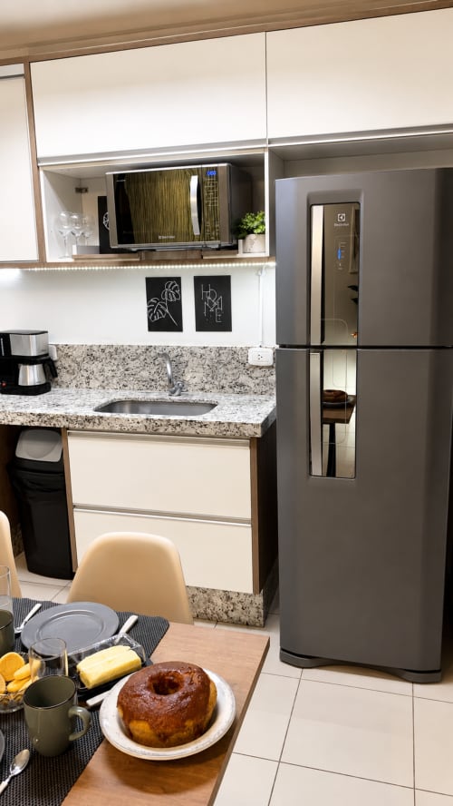 Cozinha moderna no apartamento 305 da CSS BnB em Matinhos, com geladeira em aço inoxidável, bancadas em granito e área de refeições
