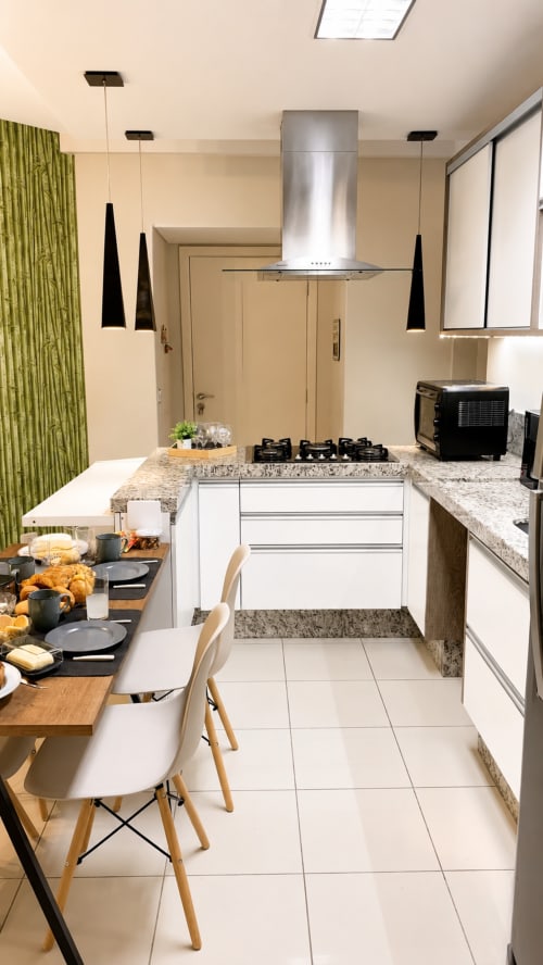 Cozinha e sala de jantar modernas no apartamento CSS Planetarium em Matinhos, com armários brancos, bancada em granito e pendentes