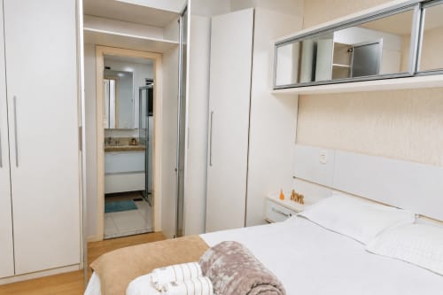 Quarto moderno do apartamento CSS Matinhos com banheiro suite, cama, guarda-roupa e espelho na acomodação 305