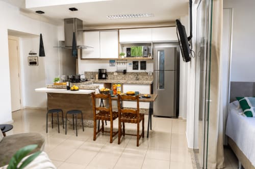 Cozinha e sala de jantar modernas no apartamento 305 do CSS Matinhos, com bancada em granito, eletrodomésticos em aço inoxidável e