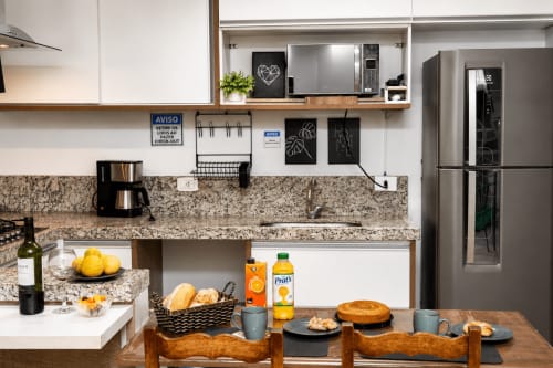 Cozinha moderna no apartamento 305 em Matinhos com bancadas de granito, eletrodomésticos em aço inoxidável e mesa de jantar