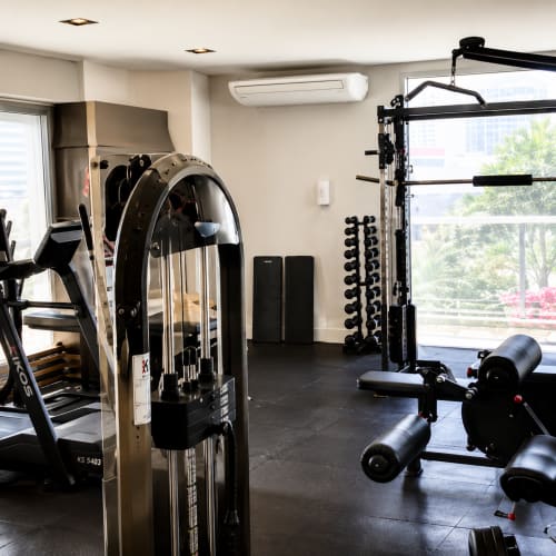 Academia moderna do apartamento CSS em Matinhos com máquinas de exercício, pesos e grandes janelas com vista para a cidade