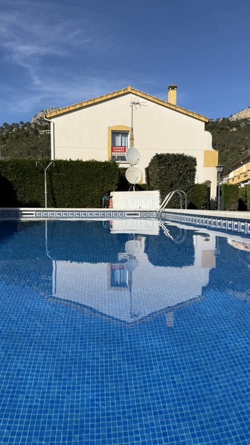 Casa de alquiler en Estartit con piscina, caseta blanca y vivienda con detalles amarillos con vistas a jardines mediterráneos