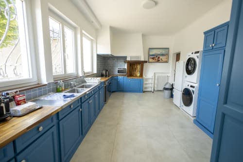 Cuisine moderne bleue de la Villa Chateaudine à l'hôtel Accolade, Châteaudun, avec lave-linge empilés et rangements