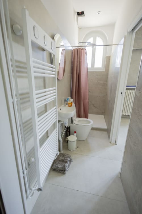 Salle de bains moderne à la Villa Chateaudine, hôtel Accolade à Châteaudun, avec sèche-serviettes chauffant blanc, toilettes, douche et rose