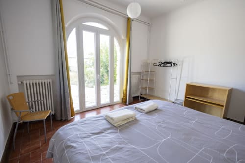 Chambre lumineuse à la Villa Chateaudine à Châteaudun avec vue sur le jardin, mobilier en bois et portes cintrées