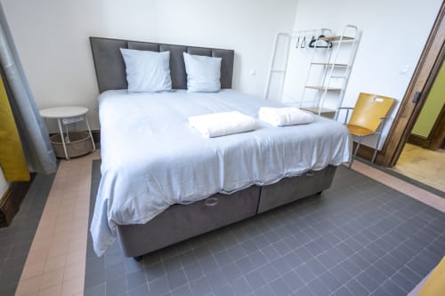 Chambre moderne de la Villa Chateaudine à l'hôtel Accolade, Châteaudun, avec lit gris et draps blancs