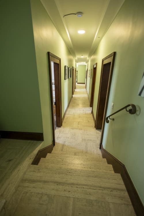 Couloir moderne aux murs vert clair, plancher en bois et portes en bois foncé à la Villa Chateaudine de l'Hôtel Accolade
