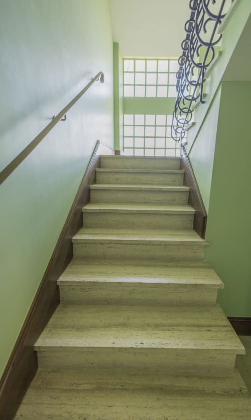 Escalier de la villa Accolade à Châteaudun avec murs verts, marches en bois, rampe métallique et puits de lumière