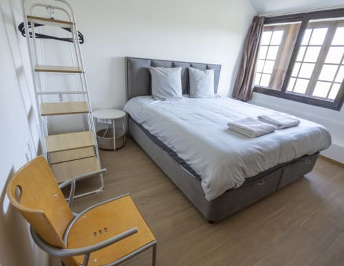 Chambre moderne à la Villa Chateaudine, hôtel Accolade, Châteaudun avec lit gris, fauteuils jaunes, échelle de mezzanine et vue sur le jardin