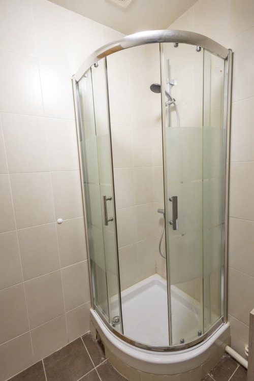 Élégante douche aux formes épurées en verre teinté dans la salle de bain de la villa Chateaudine de l'hôtel Accolade, Châteaudun, avec murs carrelés blancs et