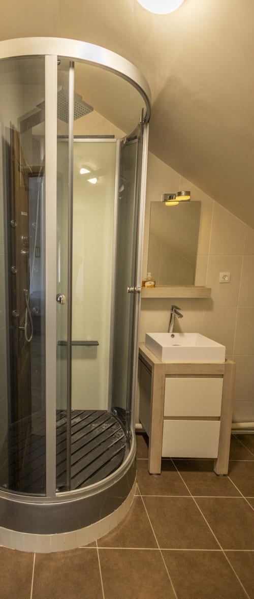 Salle de bain moderne à la Villa Chateaudine de l'hôtel Accolade, Châteaudun, avec douche en verre courbe et vasque blanche